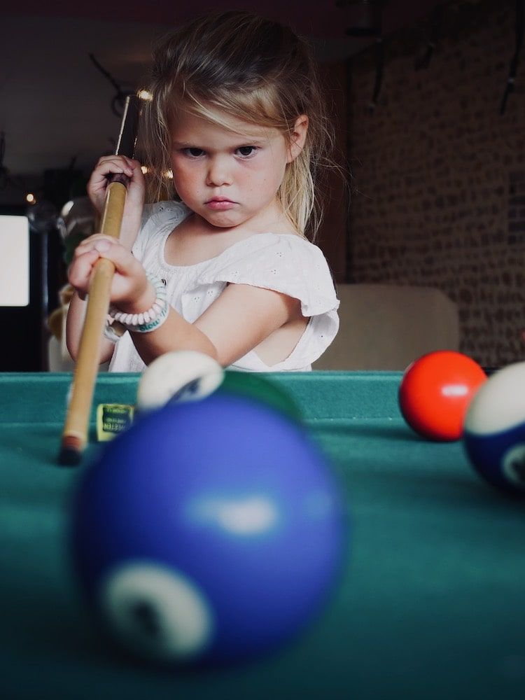 Petite fille jouant au billard