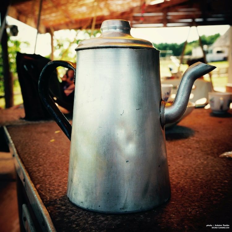 Vieille cafetière en métal sur une table. 