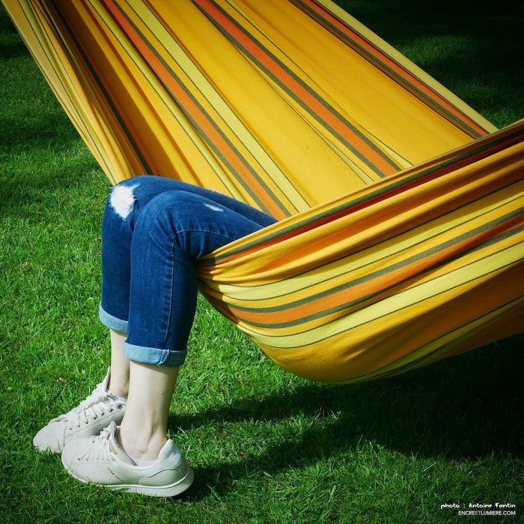 Jambes de femme sortant d'un hamac jaune.