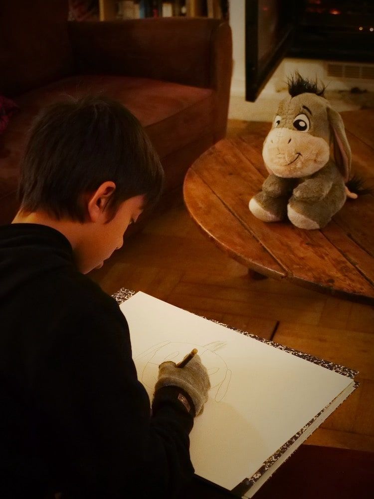 Enfant blond de 7 ans faisant ses devoirs à la maison. Photographe Normandie, Calvados.