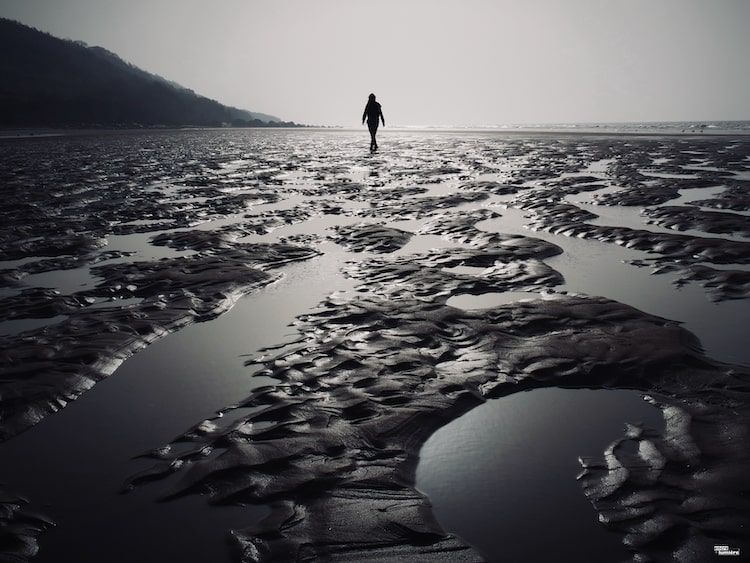 silhouette d'une femme sur une plage à marée basse