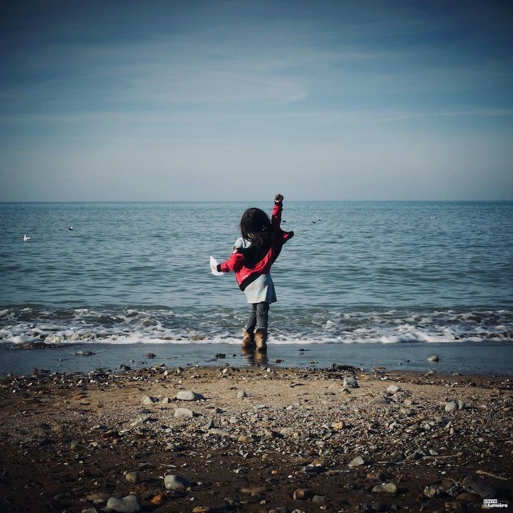 Enfant de 8 ans face à la mer le bras levé en Normandie