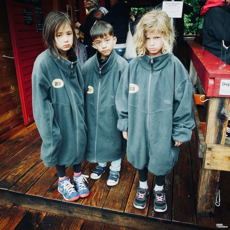 Trois enfants faisant la tête avec des gilets moches. Photo : Antoine Fantin