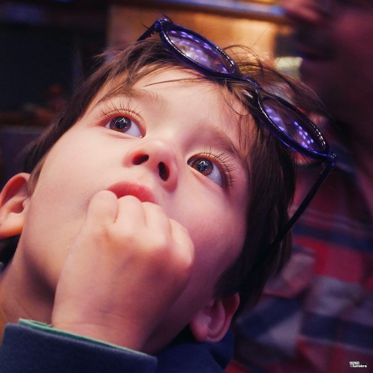 Portrait d'un enfant de 5 ans avec des yeux grands ouverts et des lunettes violettes. 