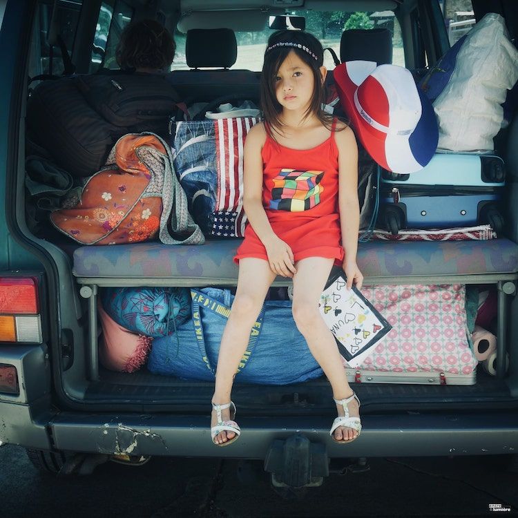 Enfant de 8 ans assise à l'arrière d'un van surchargée. Photo voyage, sur la route.