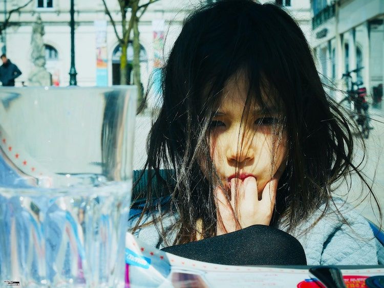 Portrait d'un enfant de 8 ans en colère assise en terrasse. Photo : Antoine Fantin (Encre & Lumière)
