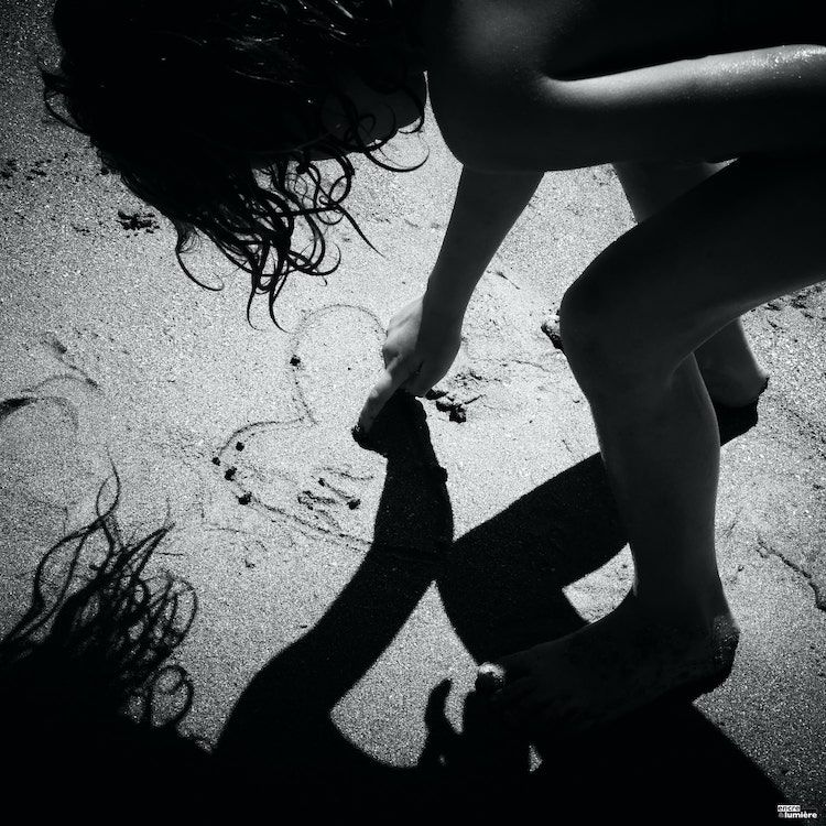 Enfant dessinant un coeur sur le sable de la plage en Normandie. Photo noir et blanc de Antoine Fantin