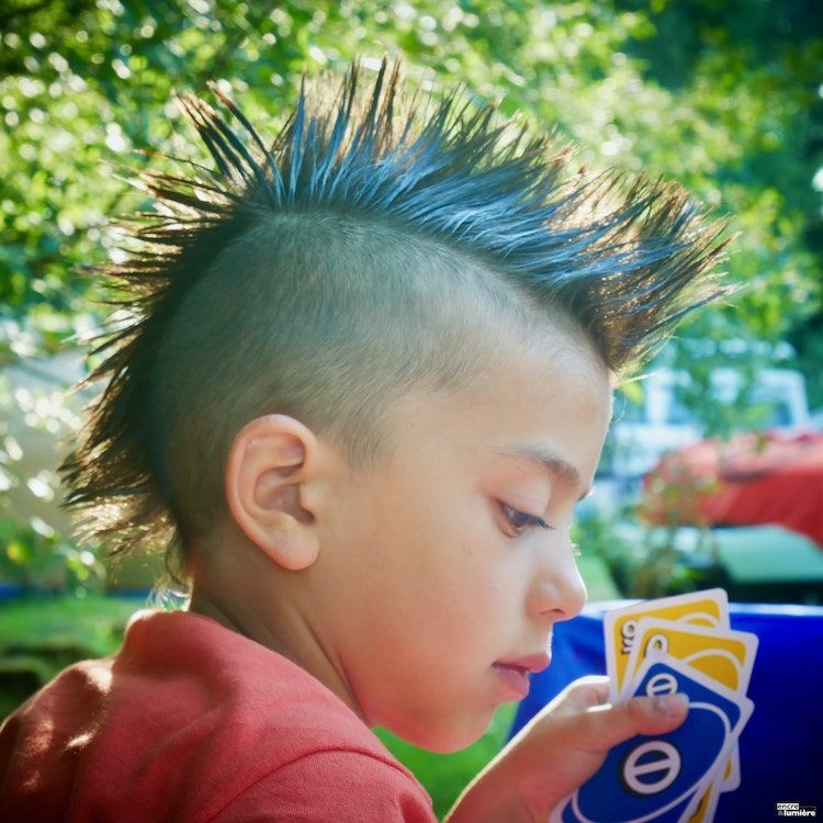 Jeune enfant avec crête de punk jouant au  jeu de carte Uno. Photographe enfant normandie. 