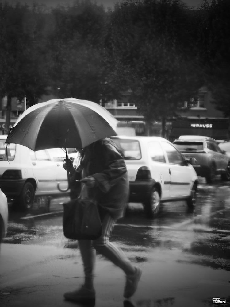 Femme avec un parapluie sous la pluie. Parking.
