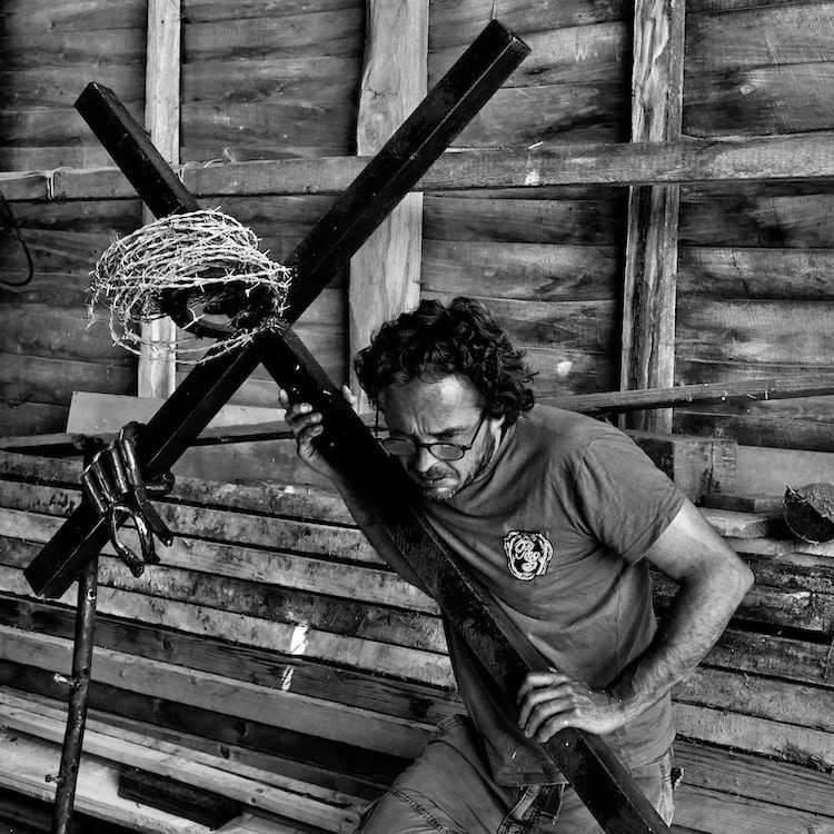 Homme portant une grande croix en métal