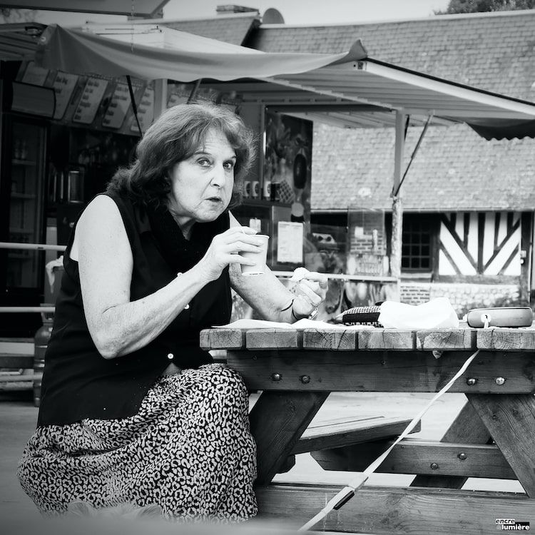 Photo de rue : femme surprise d'être photographiée en buvant son café.