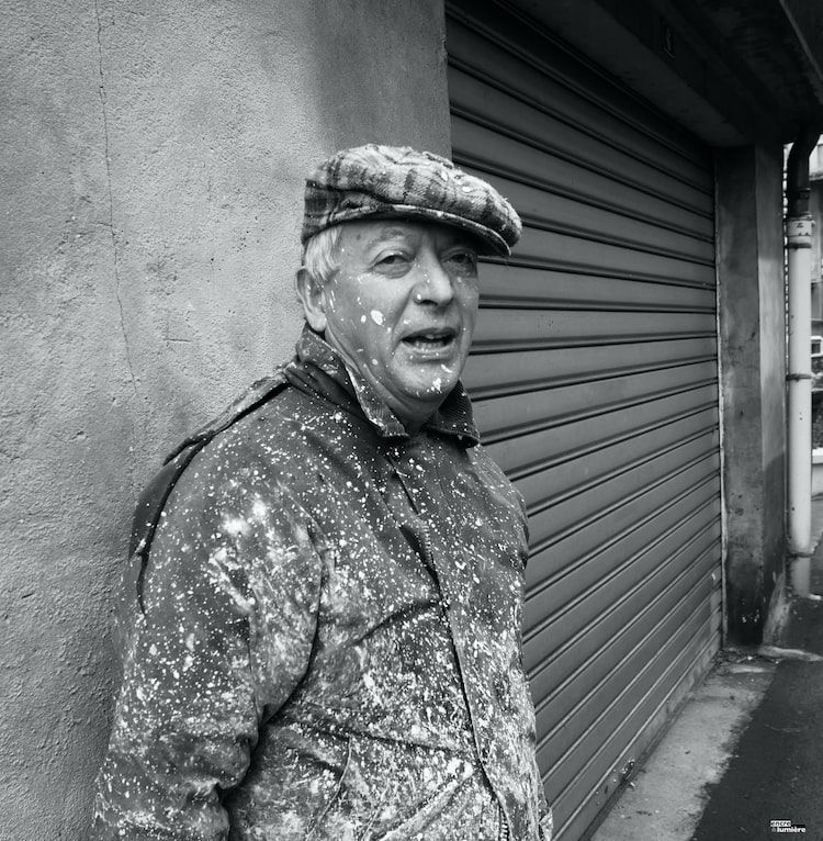 Peintre en bâtiment avec casquette recouvert de peinture blanche.